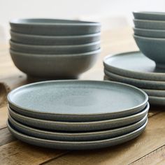 a stack of gray plates sitting on top of a wooden table