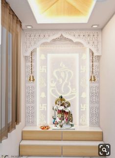 a white and gold decorated room with two statues on the bench, lights hanging from the ceiling