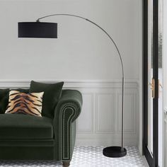 a living room with a green couch and a black floor lamp in front of it