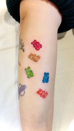 a person with tattoos on their arm has gummy bears all over her left arm