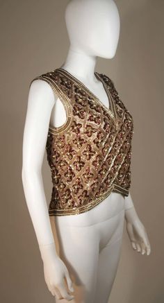 For Sale on 1stDibs - This Galanos blouse is composed of a beaded and sequin appliqued silk, in gold and burgundy hues. The top features a 3-dimensional beading technique. There Elegant V-neck Tops For Reception, Festive Embellished V-neck Top, Gold Embellished Sleeveless Top, Silk Top With Mirror Work For Wedding, Wedding Silk Top With Mirror Work, Silk Wedding Top With Mirror Work, Glamorous Embroidered Tops For Evening, Glamorous Embroidered Evening Tops, Festive Hand Embellished Tops For Reception