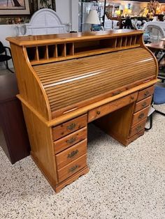 an old wooden desk with drawers in a room full of chairs and other items on the floor