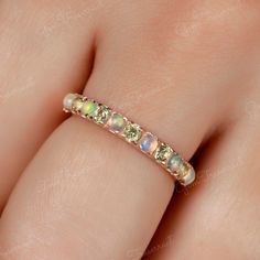 a woman's hand wearing a gold ring with multicolored stones on it