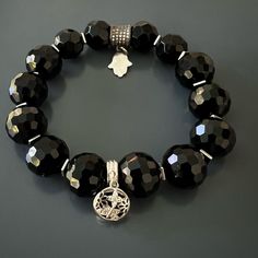 The Black protection Symbol Bracelet is great if you're looking for a sleek and stylish look. I elevated the look and feel of faceted black onyx stone beads with silver and silver and onyx butterfly charm and a sparkly Swarovski bead with hamsa charm to create this elegant piece. This bracelet is a great addition to any wardrobe and is both stylish and protective. Black Onyx Crystal resonates with the root chakra and it always has your back. Onyx Stone symbolizes change and spiritual journey. Us Elegant Obsidian Bracelets For Meditation, Luxury Silver Onyx Bracelets, Black Symbolic Bracelet Jewelry, Symbolic Black Bracelet Jewelry, Luxury Adjustable Bracelets With Charms, Luxury Adjustable Charms Bracelets, Handmade Black Bangle Charm Bracelet, Elegant Black Bangle Charm Bracelet, Spiritual Black Beaded Bracelets With Stones