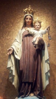 a statue of the virgin mary and child jesus in front of a mosaic wall background