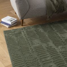 a living room area with a couch, rug and book on the floor in front of it