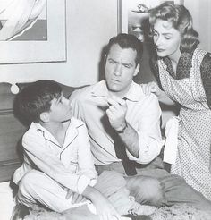 an old black and white photo of a man helping a woman put on her tie