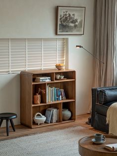 a living room with a couch, chair and bookshelf in front of a window