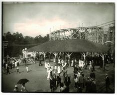 an old black and white photo of people in front of a roller coaster at a amusement park