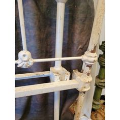 an old white iron bed frame with rusted paint on the rails and headboard