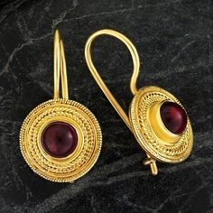 Handcrafted of a tiny disc of filigree thread, this classic Greek design highlights the beauty of a single cabochon garnet. The original Greek earrings are part of the Museum's permanent collection. 24k gold over sterling silver. Hinged backs for pierced ears. Size: 7/8 Inches. Elegant Gold Garnet Cabochon Jewelry, Gold Ruby Earrings, Pierced, Elegant Gemstone Ceremonial Earrings, Elegant Ceremonial Gemstone Earrings, Gold Ruby Round Earrings, Ceremonial Gold Gemstone Earrings, Gold Garnet Earrings As Gift, Round Filigree Temple Jewelry Earrings, Byzantine Style Gold-plated Round Jewelry