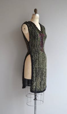 a mannequin wearing a black and green knitted dress on top of a metal stand