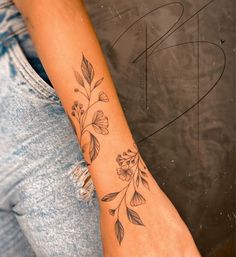 a woman's arm with flowers and leaves tattooed on the left side of her arm