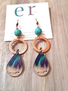 These super cute earrings are perfect for winter! They feature small copper hoops with tear drop shaped wood and resin dangles with a winter and northern lights scene. They are finished with a turquoise gemstone bead. These earrings measure 3.25" in length and will ship in a gift box or bag via USPS with tracking info provided. Small Hoop Copper Jewelry, Nickel-free Adjustable Drop Jewelry, Nature-inspired Pierced Dangle Jewelry, Unique Brown Drop Earrings, Adjustable Hypoallergenic Teardrop Jewelry, Handmade Copper Drop Earrings, Handmade Turquoise Drop Jewelry, Nickel-free Turquoise Jewelry For Crafting, Artisan Small Hoop Copper Jewelry