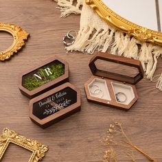 three wooden boxes with wedding rings inside sitting on a table next to some other items