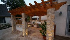 an outdoor kitchen and dining area is lit up at night with lights on the patio