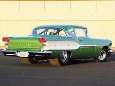 an old green and white car parked in front of a building