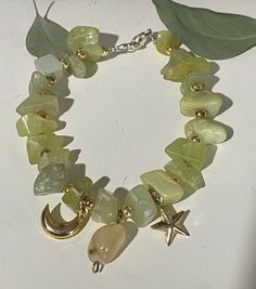 Handmade green chunky peridot rock beaded bracelet with faux gold charms of celestial designs Handmade Aventurine Round Bead Jewelry, Gold Jade Bracelets With Natural Stones, Green Dangle Jewelry With Stones, Green Dangle Stone Jewelry, Green Jewelry With Stones For May Birthstone, Green Jewelry With May Birthstone Stones, Green Stone Jewelry For May Birthstone, Green May Birthstone Jewelry With Stones, Bohemian Jewelry With Moon Charm And Round Beads