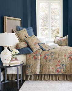 a bedroom with blue walls and floral bedding in front of a large window,