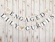 an engaged couple banner hanging on a wooden wall with hearts and the words engaged newly married