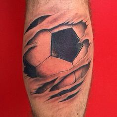 a man's leg with a tattoo of a soccer ball breaking through the skin