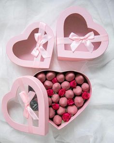 two pink heart shaped boxes filled with chocolates