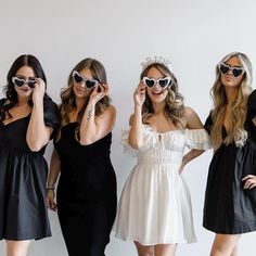 three women in dresses and sunglasses posing for the camera with their hands on their faces