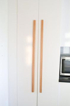 two wooden sticks sticking out of the side of a white wall next to a microwave