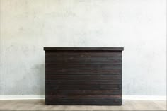 a wooden chest sitting on top of a hard wood floor next to a white wall