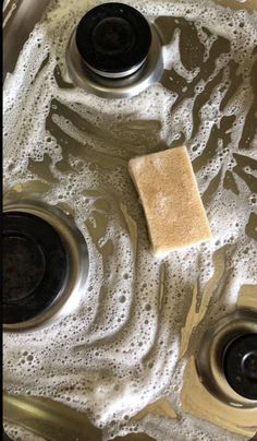 a close up of a sink with soapy water on the bottom and two burners