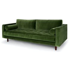 a green velvet couch with wooden legs