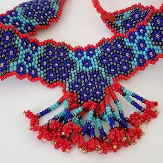 Vintage fringe choker necklace, in classic boho, southwestern style vibe. Adjustable with tie back closure. In very good pre-owned condition. Red, royal and turquoise blue, hematite silver, and yellow/gold accents. Hundreds of woven glass seed beads, finished with a red cord tie. Red is richer in person, and not orange. Bead cluster ball ends for a great look! Beaded band portion is approximately 9 1/4" x 1" wide. Fringed center portion hangs down approximately 2 3/8" from top of band. Cords are 10" long, excluding beaded ends. Necklace length is very adjustable. Beautiful colors and pattern--classic beaded fringe choker! Will be boxed. NOTE: Orders are sent via USPS Ground Advantage. For faster shipping, choose Priority Mail at checkout. Etsy's estimated delivery dates are not guaranteed. Artisan Beaded Adjustable Bib Necklace, Artisan Beaded Bib Necklace With Adjustable Fit, Handwoven Red Beaded Necklace For Festivals, Red Handwoven Beaded Necklace For Festivals, Traditional Red Beads Choker, Handwoven Blue Beaded Necklaces For Festivals, Festival Beaded Bib Necklace, Handwoven Blue Beaded Necklace For Festival, Blue Handwoven Beaded Necklace For Festivals