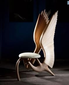 an unusual chair with wings on it in the middle of a dark room at night