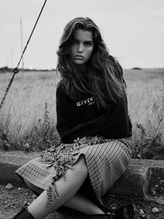 a woman is sitting on a stone wall