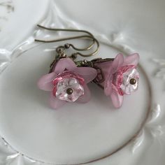 "Pretty in Pink... Add some spring to your wardrobe with these lovely double pink blossoms. Delicate pink petals surround bright pink and white centers. Antique brass filigree caps adorn the tops and a tiny green bead adds a bit of spring pop. These earrings are very lightweight and comfortable to wear. Perfect for a garden wedding, or a gift for a nature lover. And don't forget...Mother's Day is just around the corner. Drop length from bottom of antique brass french earwire: 1\" (25mm) Prefer a Pink Petal-shaped Earrings For Spring, Feminine Flower Earrings With Ear Wire For Gifts, Delicate Pink Flower Earrings For Spring, Pink Earrings With Handmade Flowers For Spring, Pink Handmade Flower Earrings For Spring, Spring Pink Earrings With Handmade Flowers, Feminine Flower-shaped Earrings For Gifts, Feminine Pink Jewelry With Handmade Flowers, Pink Feminine Flower Drop Earrings