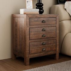 a small wooden chest of drawers next to a couch with a lamp on top of it