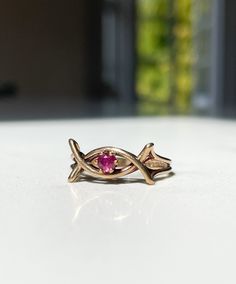 A 9ct gold ruby dress ring.  The ring is hallmarked for Sheffield and date stamped to 1979. There is a pink-ish red ruby stone surrounded by a decorative gold banded frame, reminiscent of a celtic twist.  Current size N1/2. Approximate weight is 2.4g. This ring comes packaged in our branded Forest & Fox ring boxes which are then securely posted with discreet, unbranded, outer packaging. We can offer resizing for some items for an extra charge (depending on the level of resizing needed), which is Pink 14k Stamped Promise Ring, Hallmarked Rose Gold Ruby Ring, Hallmarked Red Ruby Ring In 14k Gold, Formal Pink Gold Ruby Ring In 14k Gold, Pink Ruby Ring In 14k Gold, Formal 14k Pink Gold Ruby Ring, Pink Ruby Ring Stamped 14k For Anniversary, 14k Gold Hallmarked Ruby Promise Ring, Pink Ruby Ring In 14k Gold For Anniversary