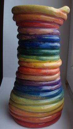 a stack of multicolored ceramic vases sitting on top of a white table