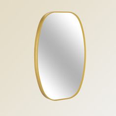 an oval mirror hanging on the wall with a gold rim around it's edge