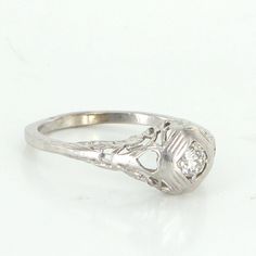 a white gold ring with an old cut diamond in the center, on a white background