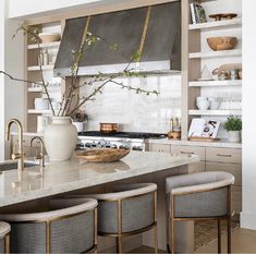 a kitchen with marble counter tops and gold accents on the cabinets, along with stools