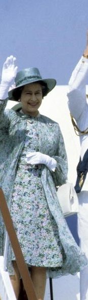 two women in dresses and hats wave from the deck of a boat while another woman waves