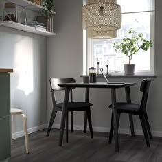 a table with two chairs and a potted plant in the corner next to it