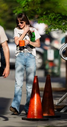 a woman is walking down the street with her hand on her face while holding a beer