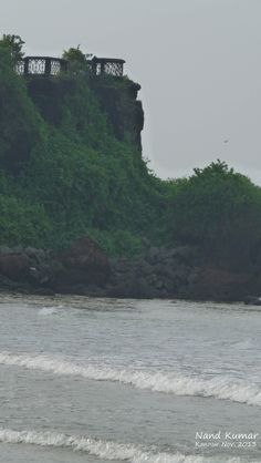 a person riding a surfboard on top of a body of water near a cliff