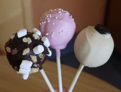 three marshmallow lollipops on a stick with white and chocolate topping