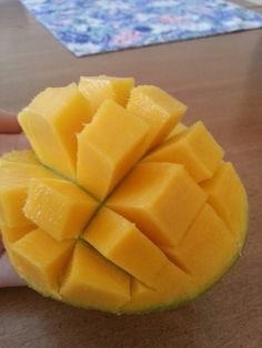 a person holding a piece of fruit on top of a wooden table