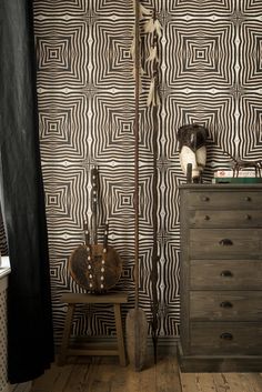 a room with a dresser, guitar case and wallpaper