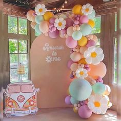 an arch made out of balloons and flowers with a vw bus in the background