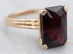 "This ring features a simple and classically designed mounting, the structural openwork shoulders lend a sense of light and grace to the mounting. Cut into a classic elongated emerald cut, the deep red cherry garnet in the center adds a lovely pop of color and also an interesting shape to a simple ring! Metal: 14K Yellow Gold Gem: Garnet 4.60 Carats Gem Measurements: 7.1 x 11.1 mm, Emerald Cut Ring Size: 5.25 Marks: \"14KP 585\" Stamped on the inside band To view a video of this piece check out the link below: https://vimeo.com/818451840 SKU #: A25481 Each piece has been identified and graded by a Graduate Gemologist who has been certified by the Gemological Institute of America (GIA). We have six brick-and-mortar storefronts in Maine, Massachusetts, and New Hampshire and have been in busi Opal Solitaire Ring, Garnet Birthstone, Right Hand Ring, Red Stone Ring, Post Grad, Emerald Cut Rings, Simple Ring, Right Hand Rings, Hand Ring